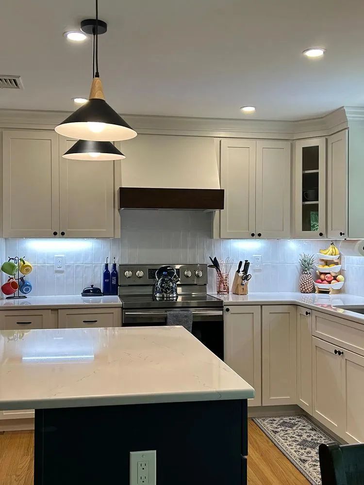 Modern kitchen with white cabinets, stainless steel appliances, and a navy island.