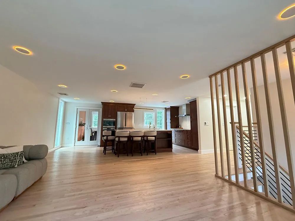 Spacious open-concept kitchen and living area with wood floors, recessed lighting, and a decorative slatted partition.