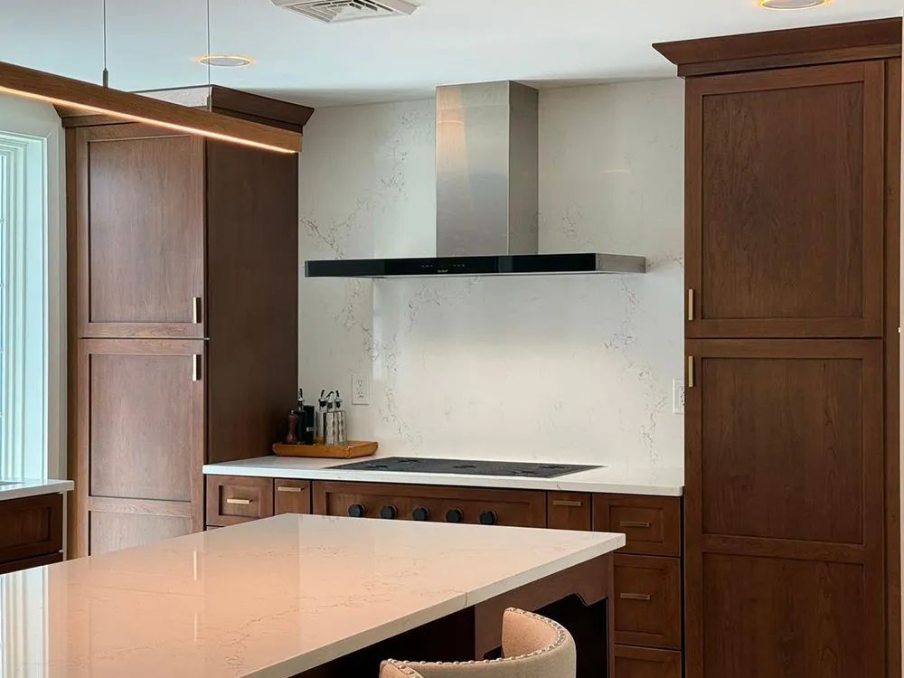 Kitchen with dark wood cabinets, white countertops, stainless steel range hood, and a white island.