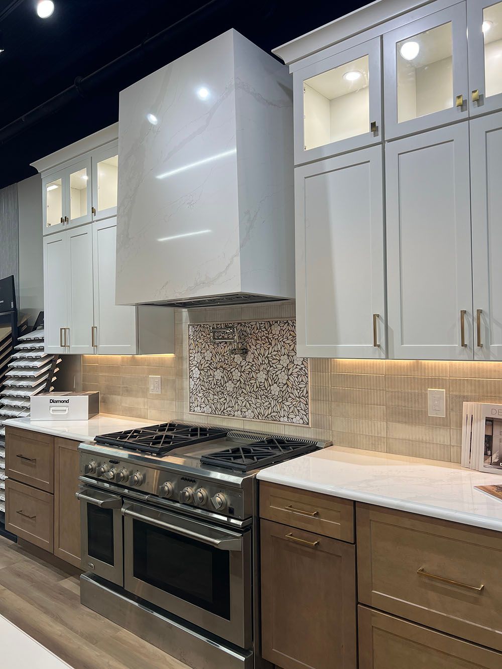 Modern kitchen with white cabinets, stainless steel stove, mosaic backsplash, and marble countertops
