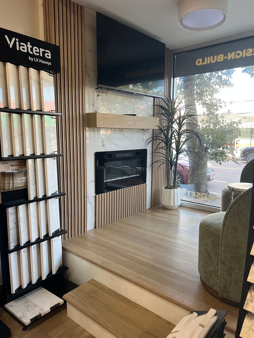 Cozy showroom fireplace seating area with striped wood wall, TV, and large front windows