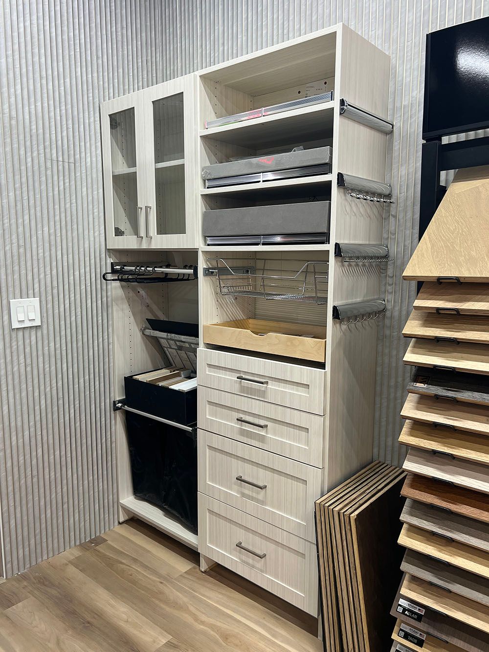 Custom closet with shelves, drawers, hanging rods, and cardboard samples in a small storage room.