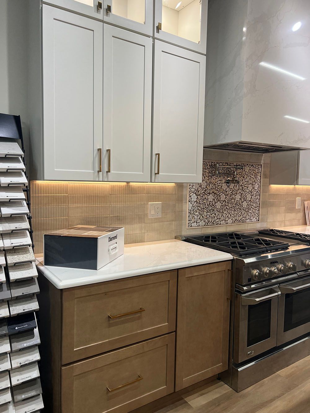 Modern kitchen with white cabinets, marble countertop, tile backsplash, and stainless steel stove and oven.