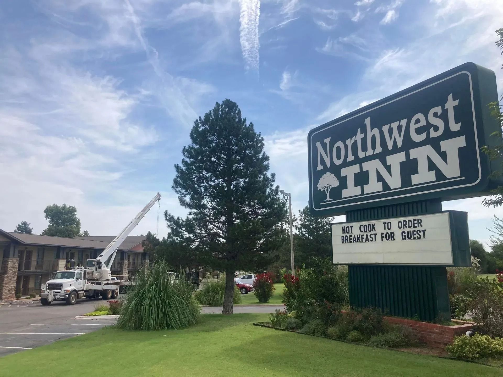 Northwest Inn sign; tree and truck with lift; cloudy sky background. 