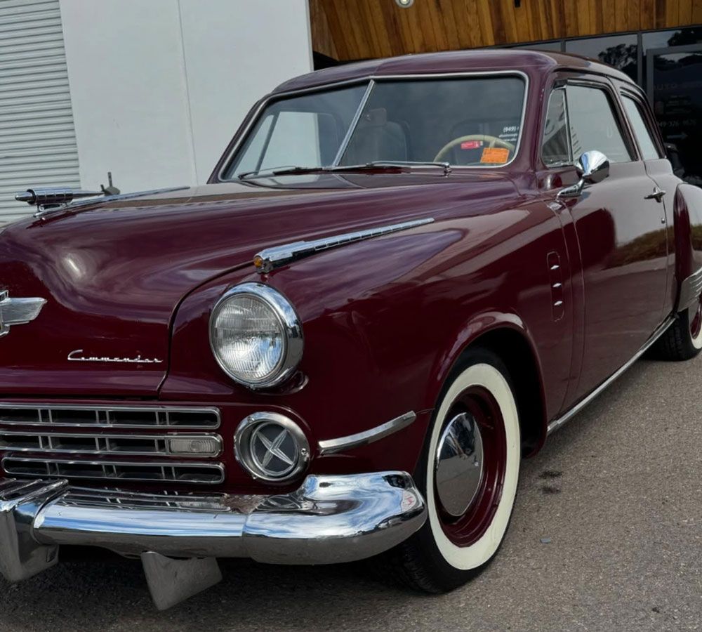 Maroon 1947 Studebaker Commander coupe with chrome accents and whitewall tires.