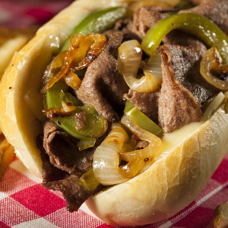 A beef sandwich with peppers onions and cheese on a bun