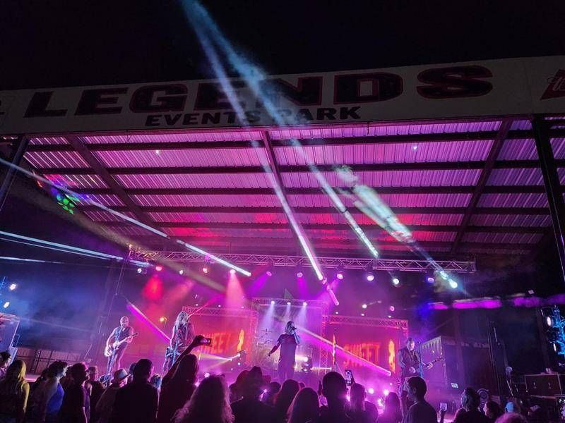 A crowd of people watching a band on stage at legends event park