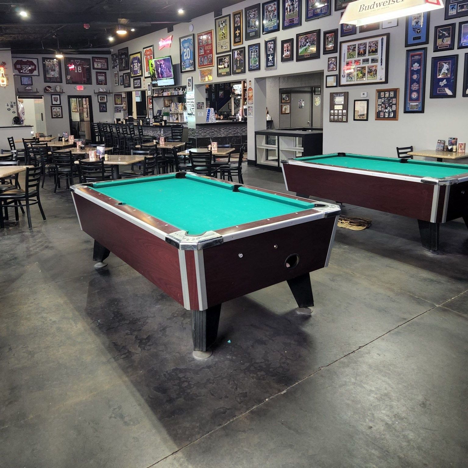 Two pool tables in a room with pictures on the wall