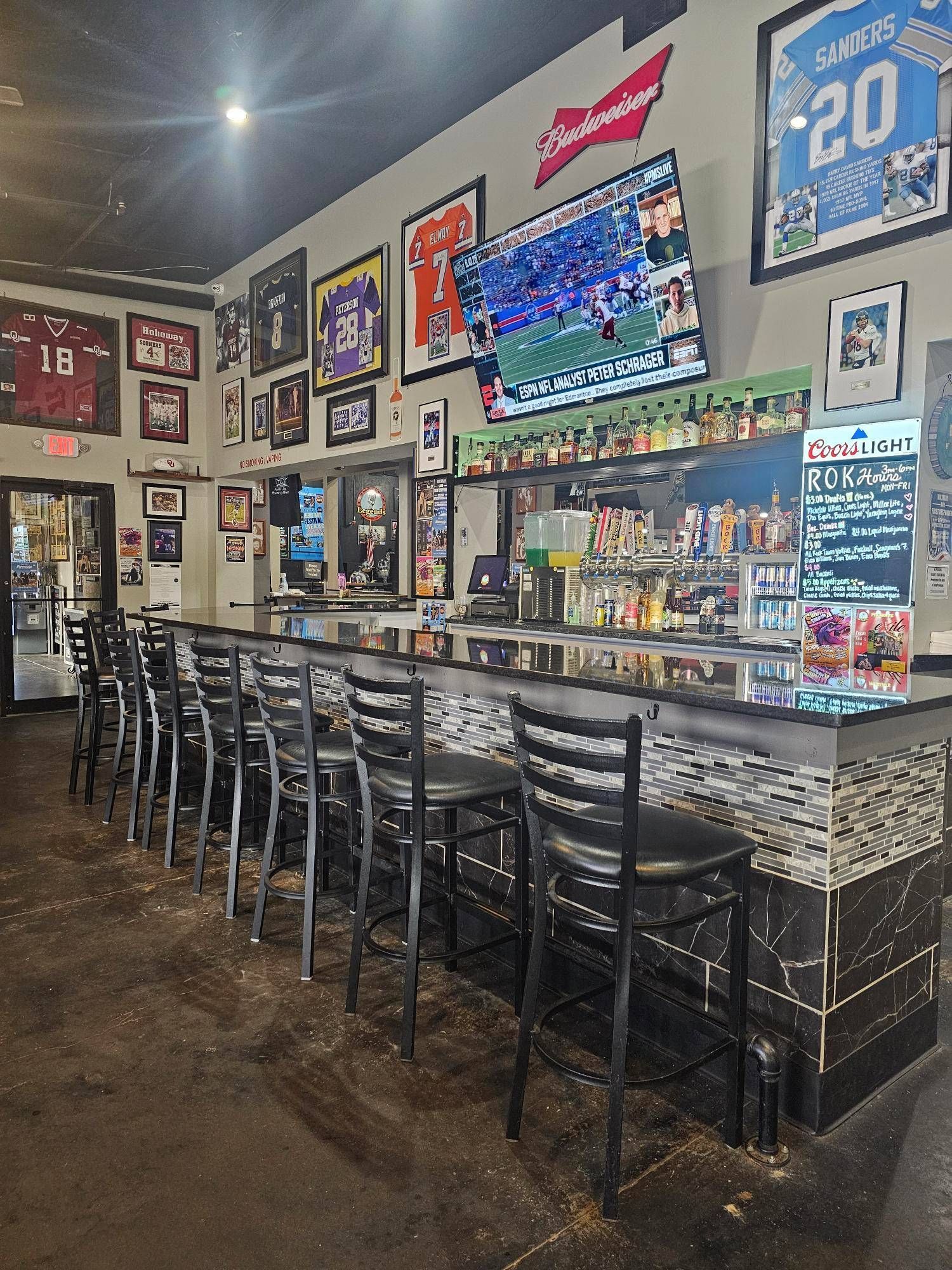 A bar with a lot of chairs and a television on the wall.