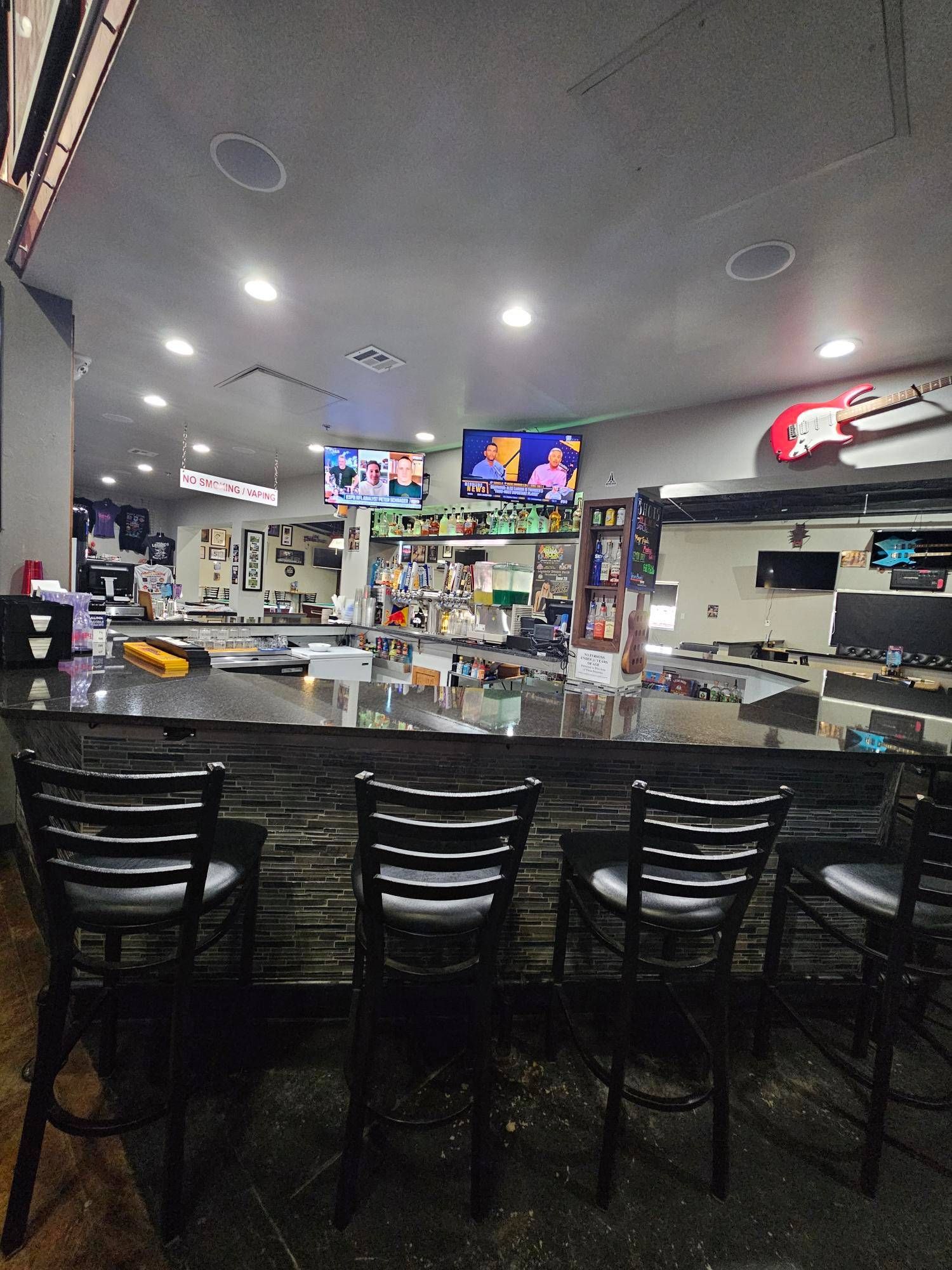 A bar with a long counter and chairs in a restaurant.