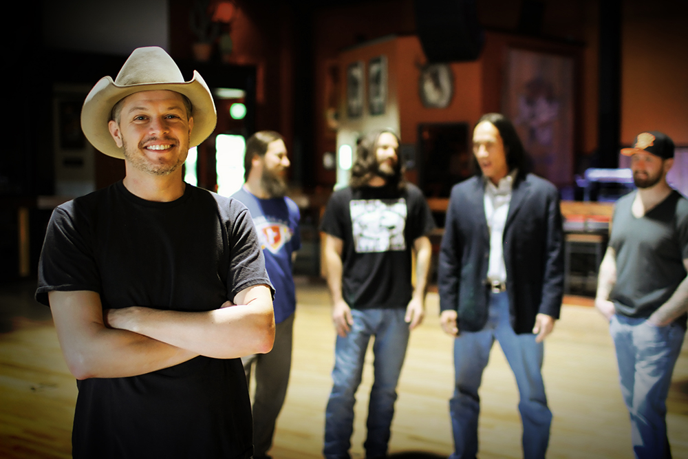 A man in a cowboy hat is standing in front of a group of men.