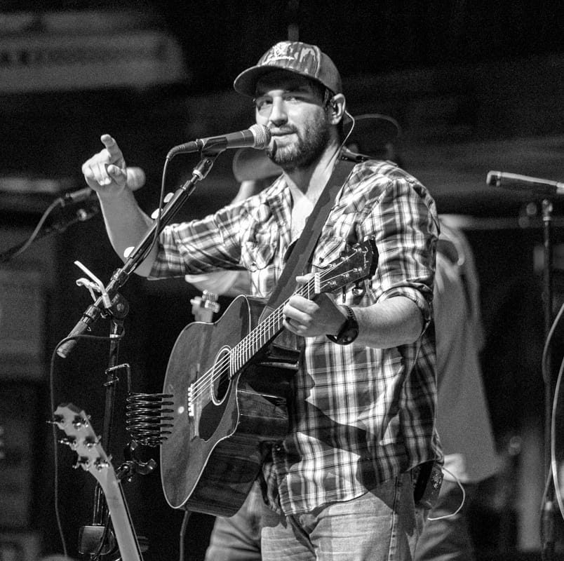 A man singing into a microphone while holding a guitar