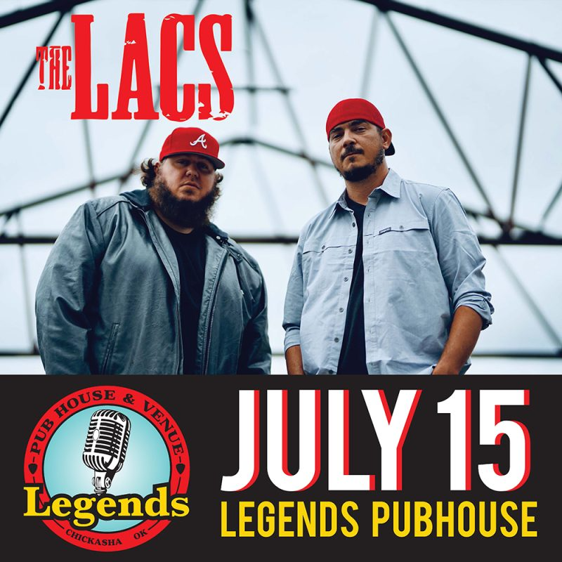 Two men standing next to each other in front of a sign that says july 15 legends pubhouse