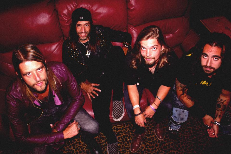 A group of men are posing for a picture on a red couch