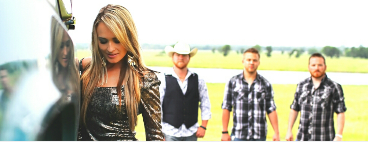 A group of men and a woman are standing in a field.