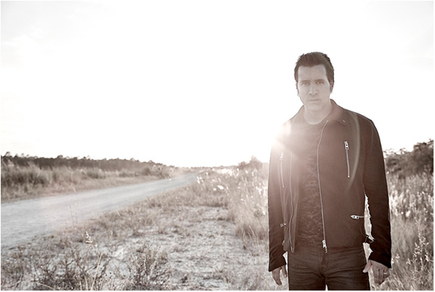 A man in a black jacket is standing in the middle of a field.
