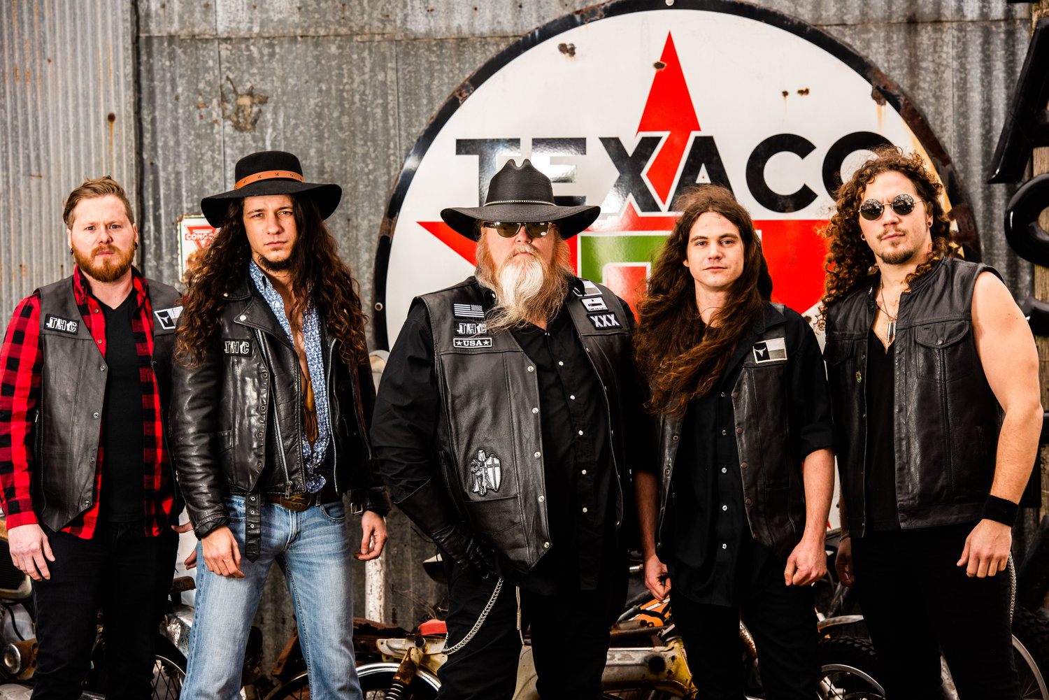 A group of men are posing for a picture in front of a texaco sign.