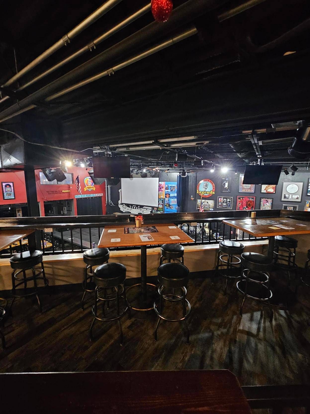 A restaurant with tables and stools and a projector screen on the wall.