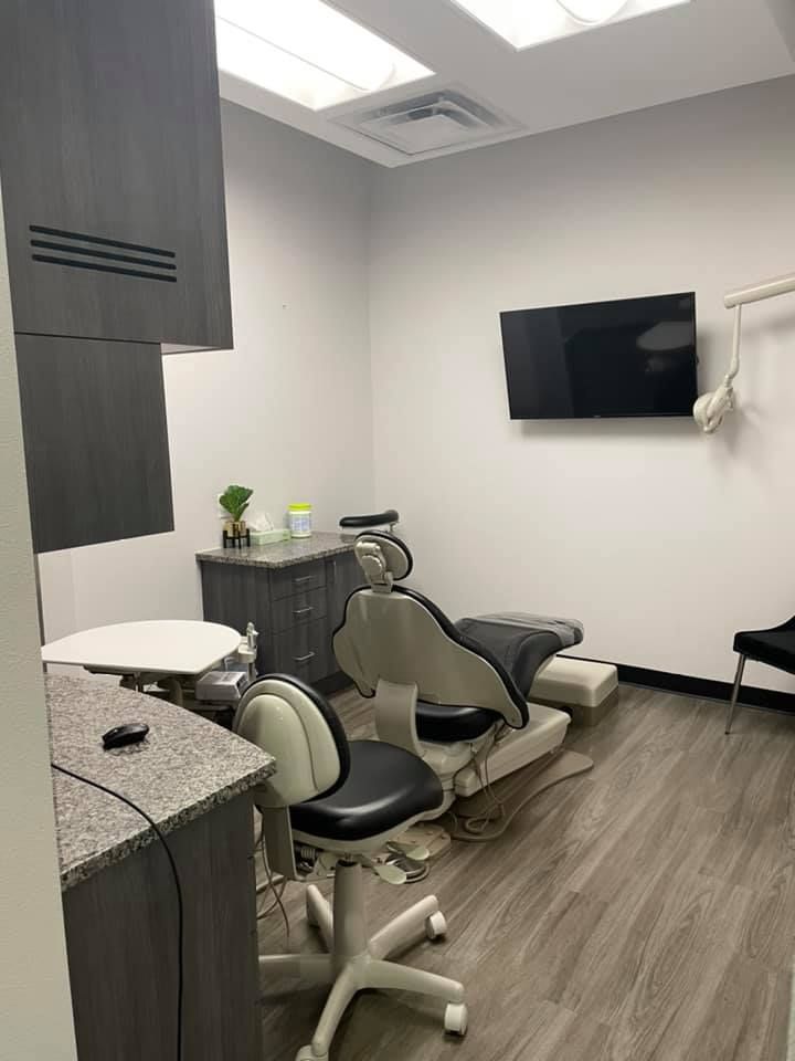 A dental office with a dental chair and a television on the wall.