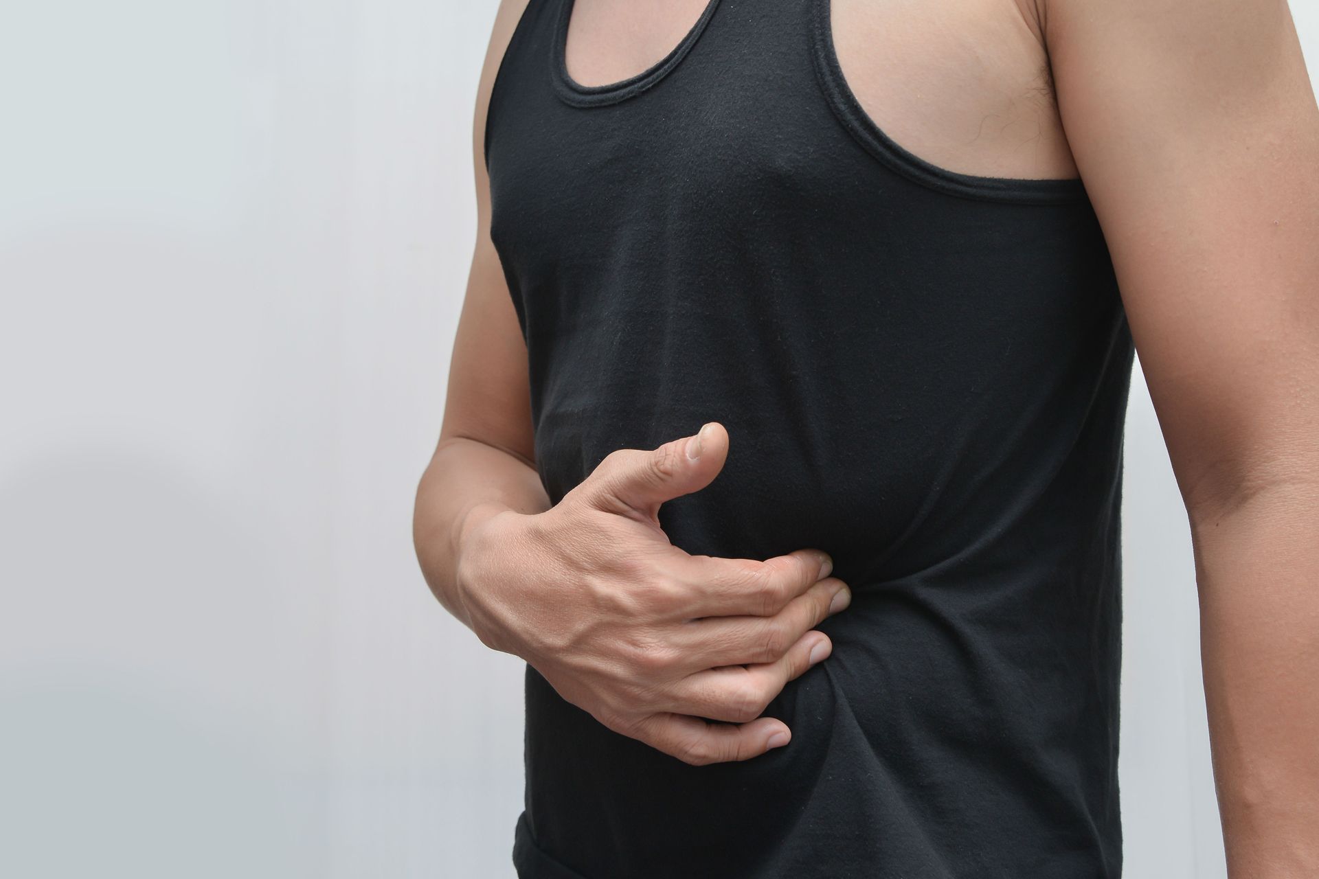 Person in black tank top clutching their side.