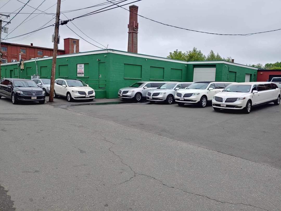 A row of cars are parked in front of a green building.