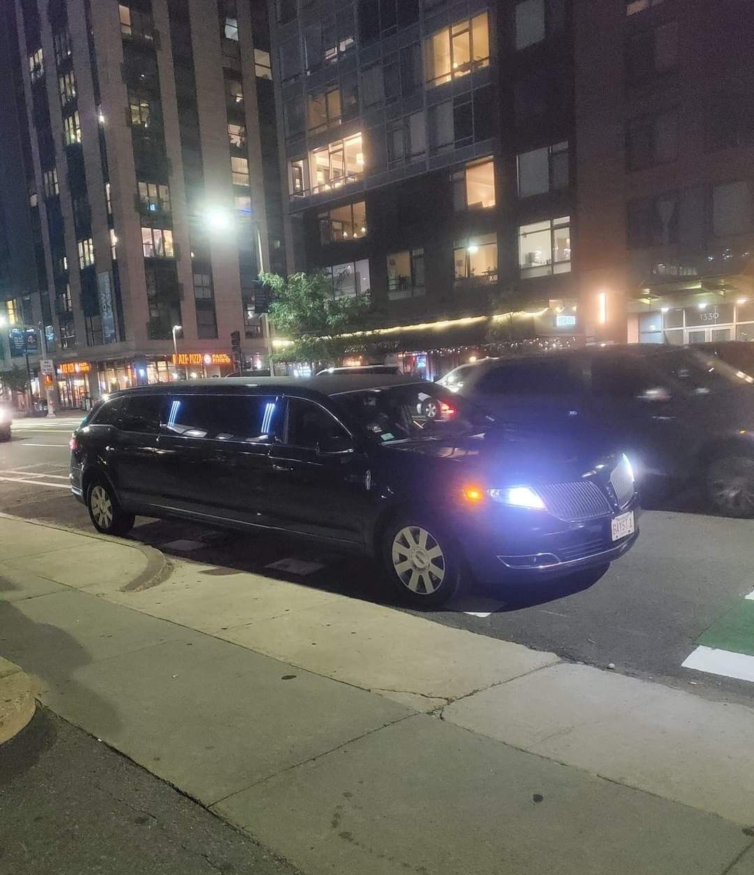 A limousine is parked on the side of the road at night