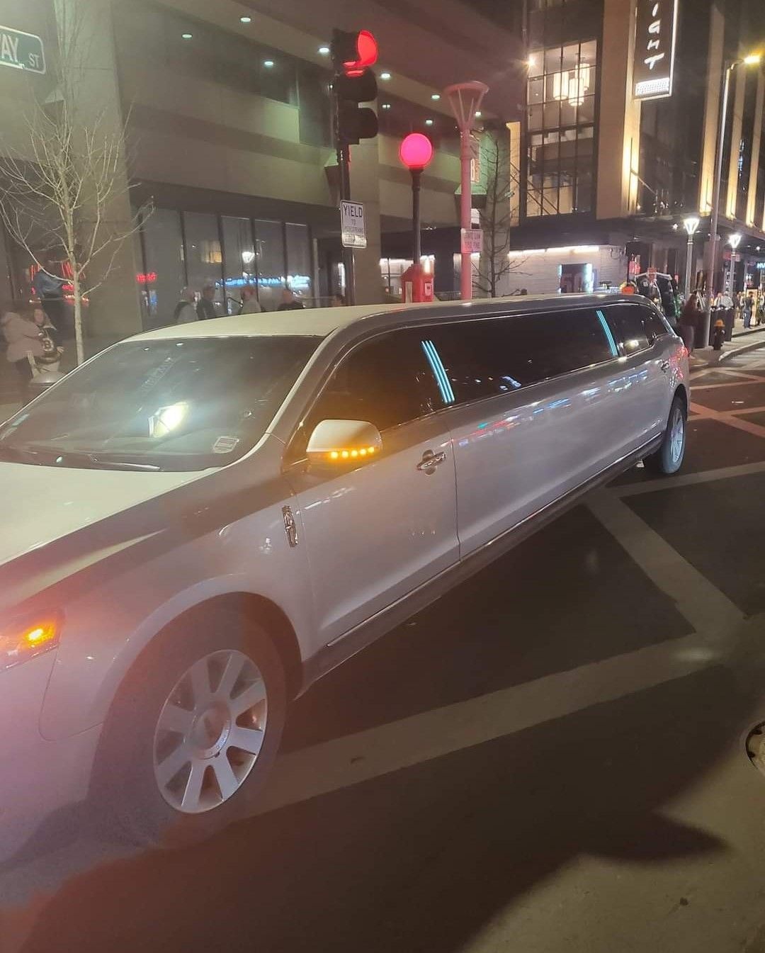 A white limousine is parked on a city street at night.