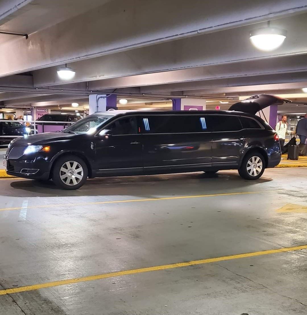 A black limousine is parked in a parking garage