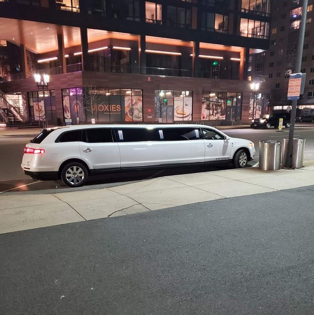 A white limousine is parked on the side of the road