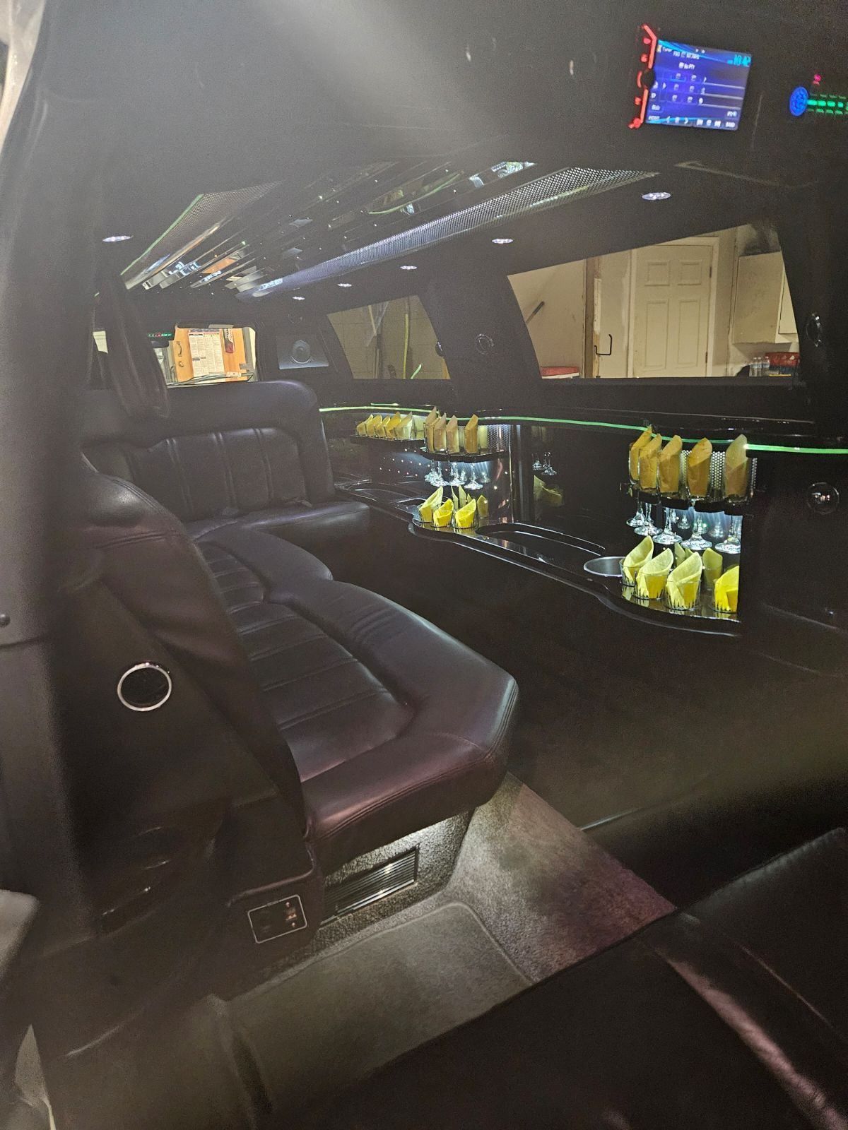 The inside of a limousine with a long table and a television.