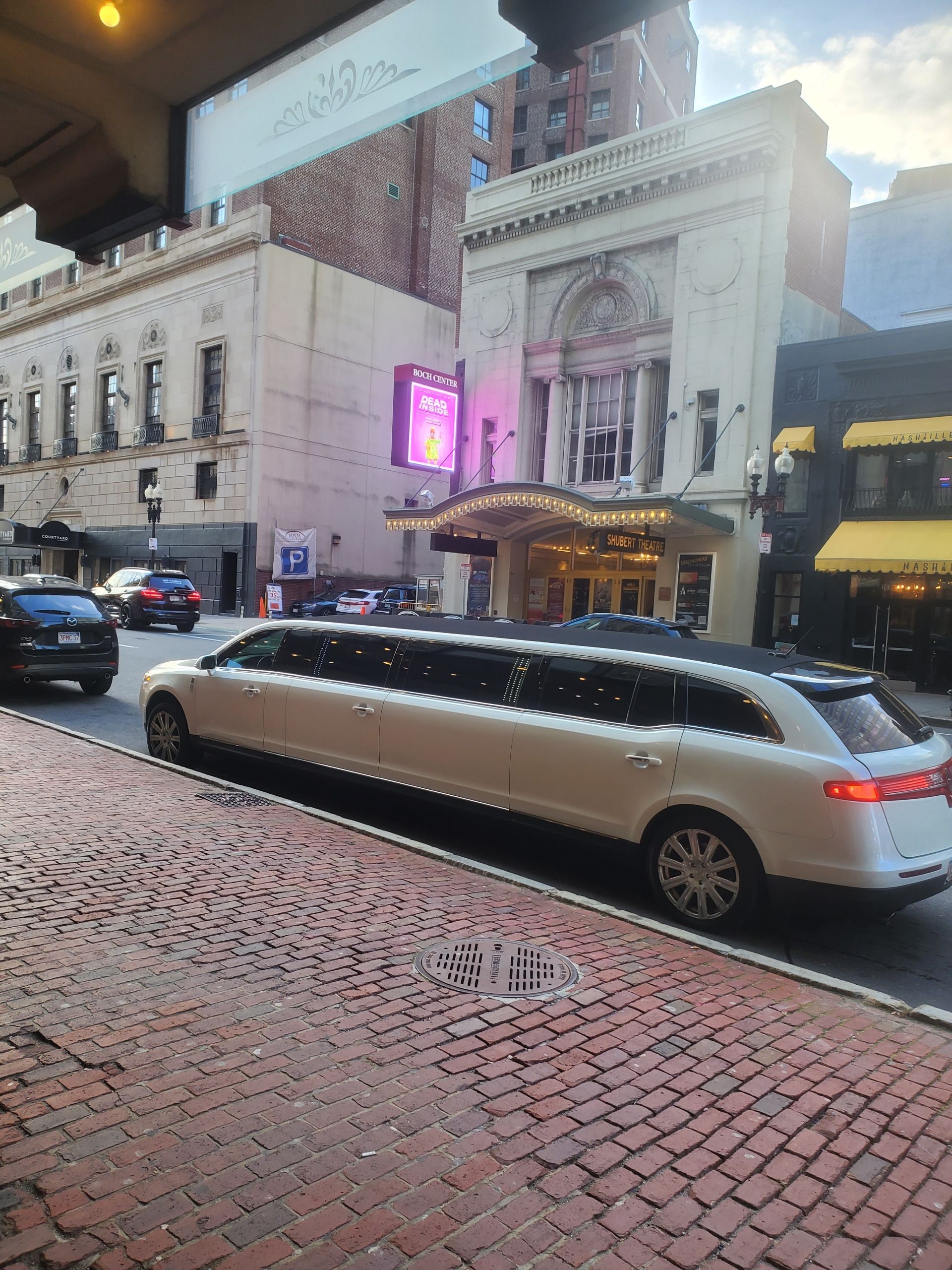 A white limousine is parked in front of a building