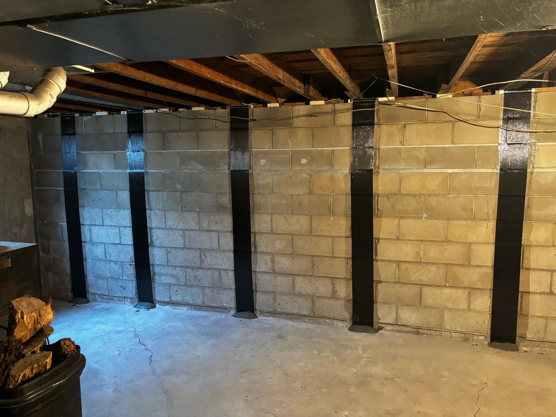 Unfinished basement with cinder block walls, exposed joists, and concrete floor.