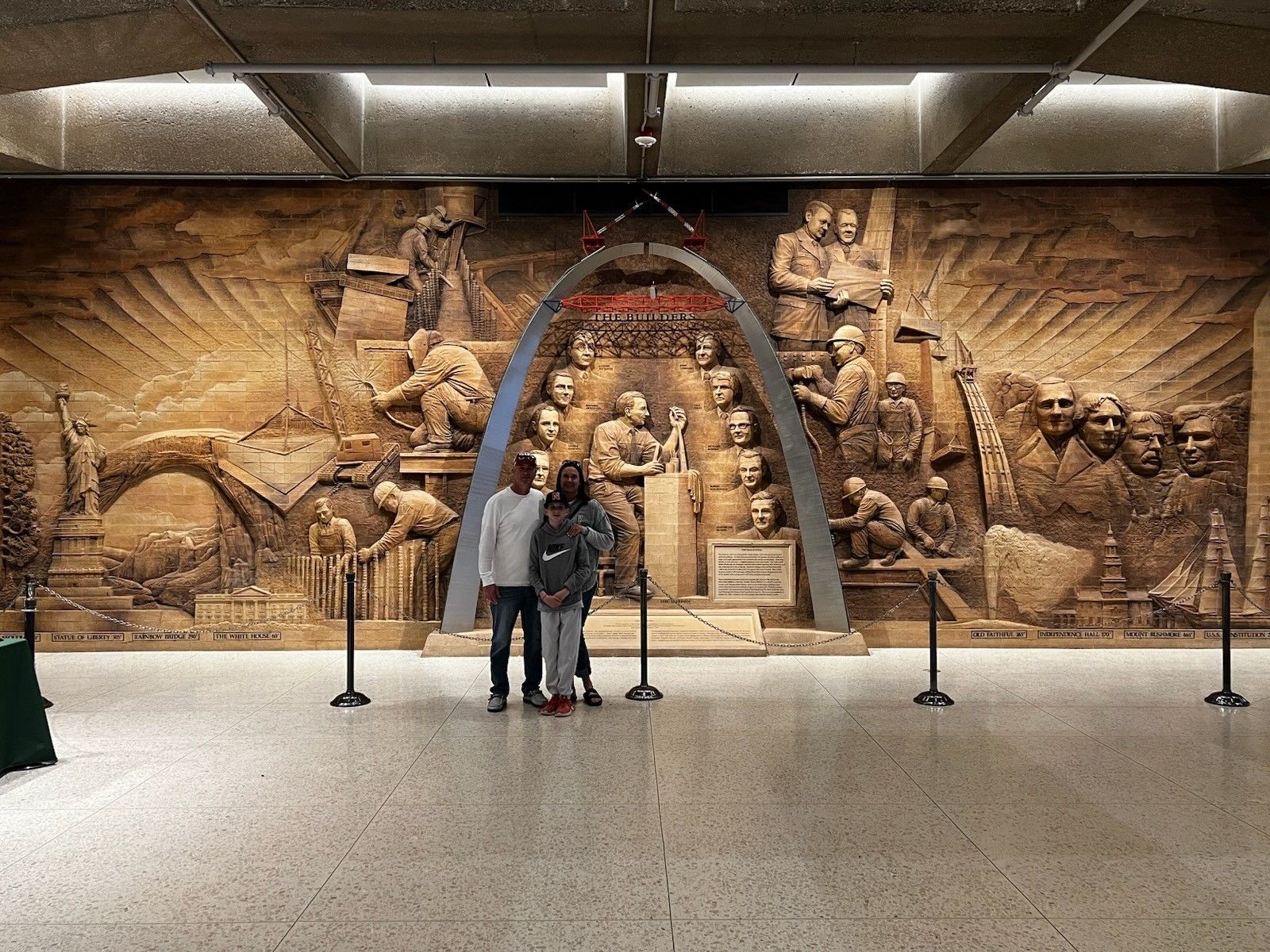 Museum hall with a large carved stone mural and two people standing in front of it