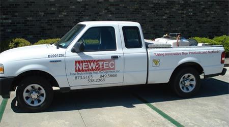 White New Tec pickup truck with logo parked outside.