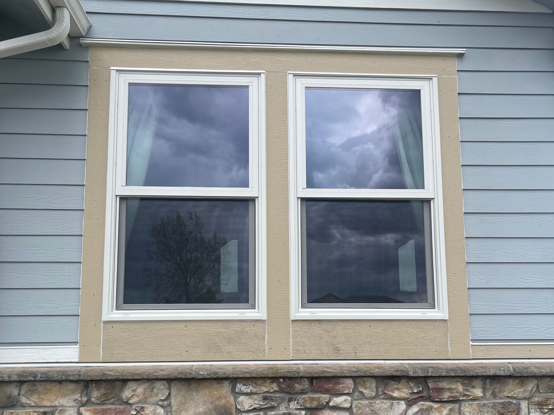 There are two windows on the side of a house.