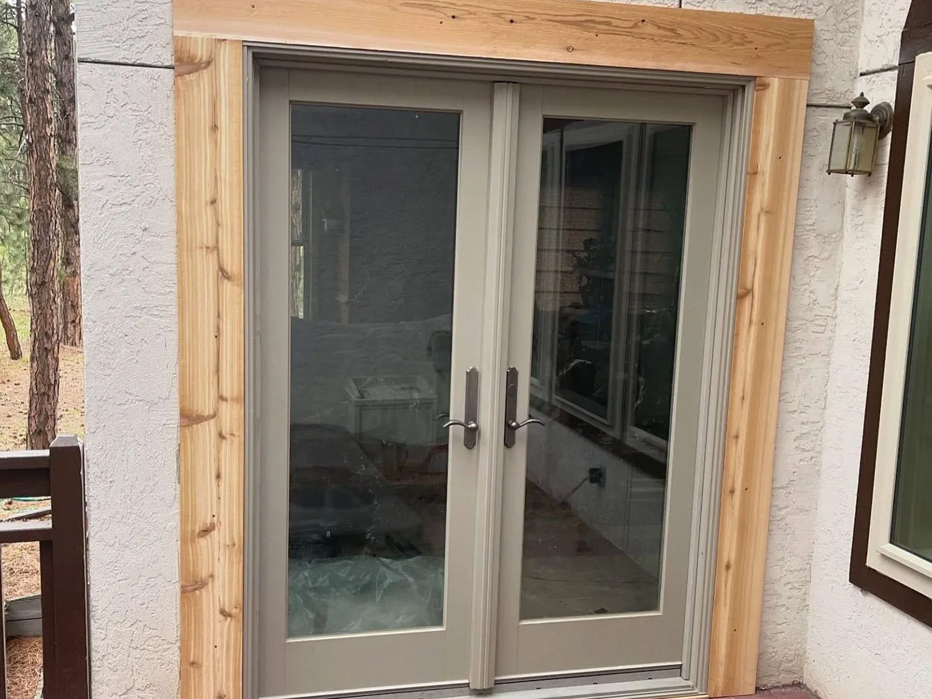 A patio door with a wooden frame is being installed on a house.