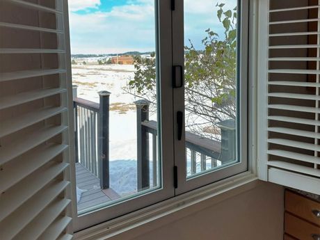 A window with shutters open and a view of a deck