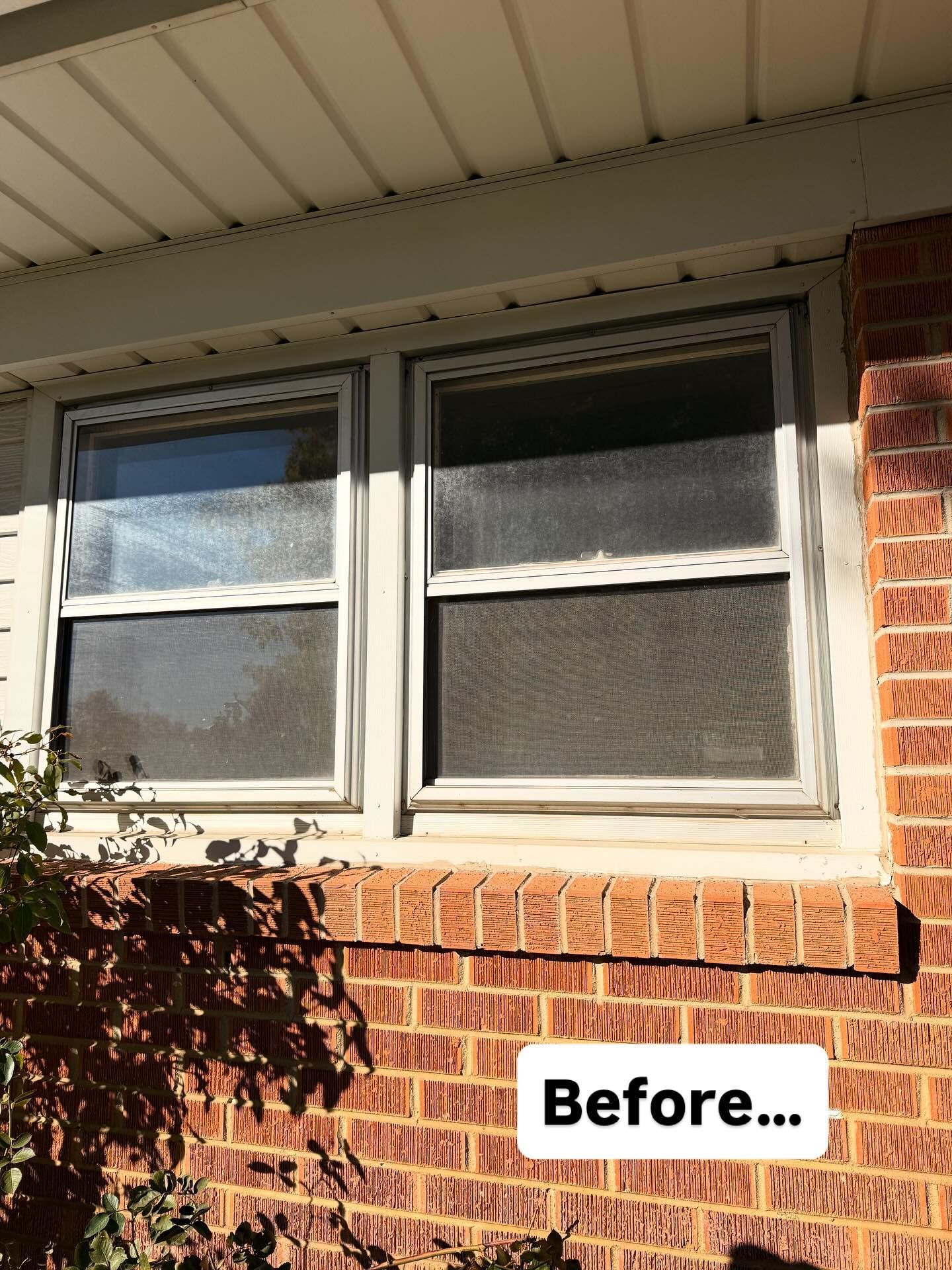 Two rectangular windows with white frames set in brick and beneath white siding
