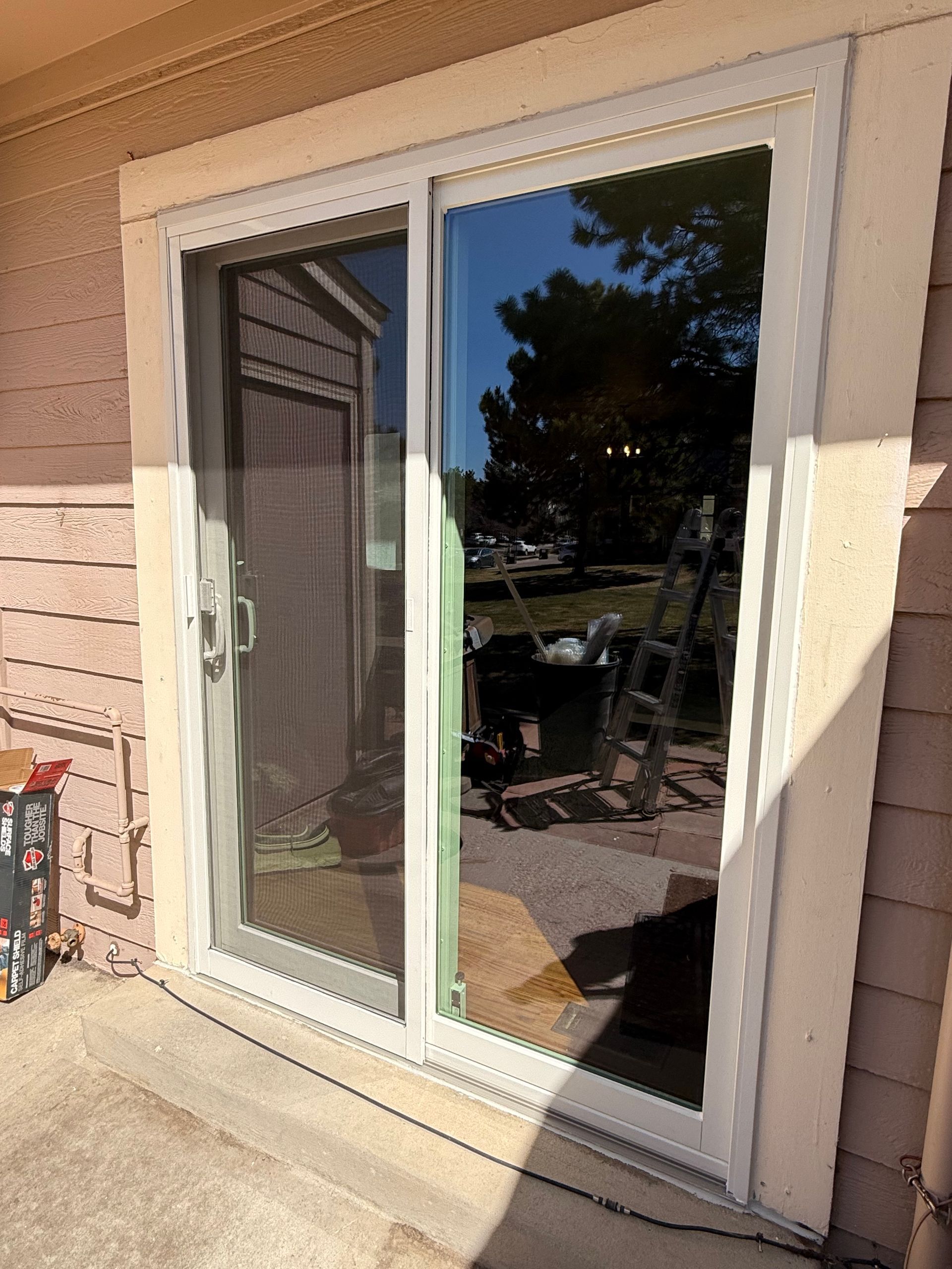A white sliding glass door is sitting on the side of a house.