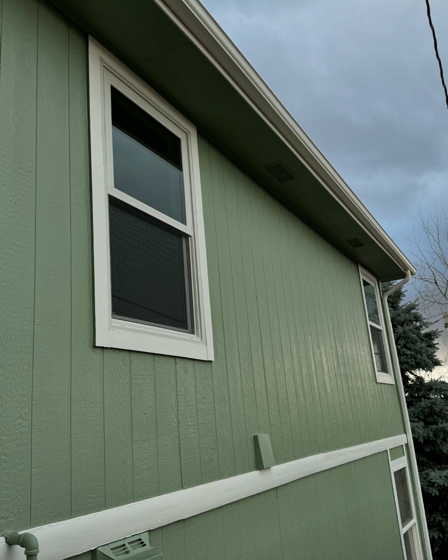 A green house with white trim and two windows