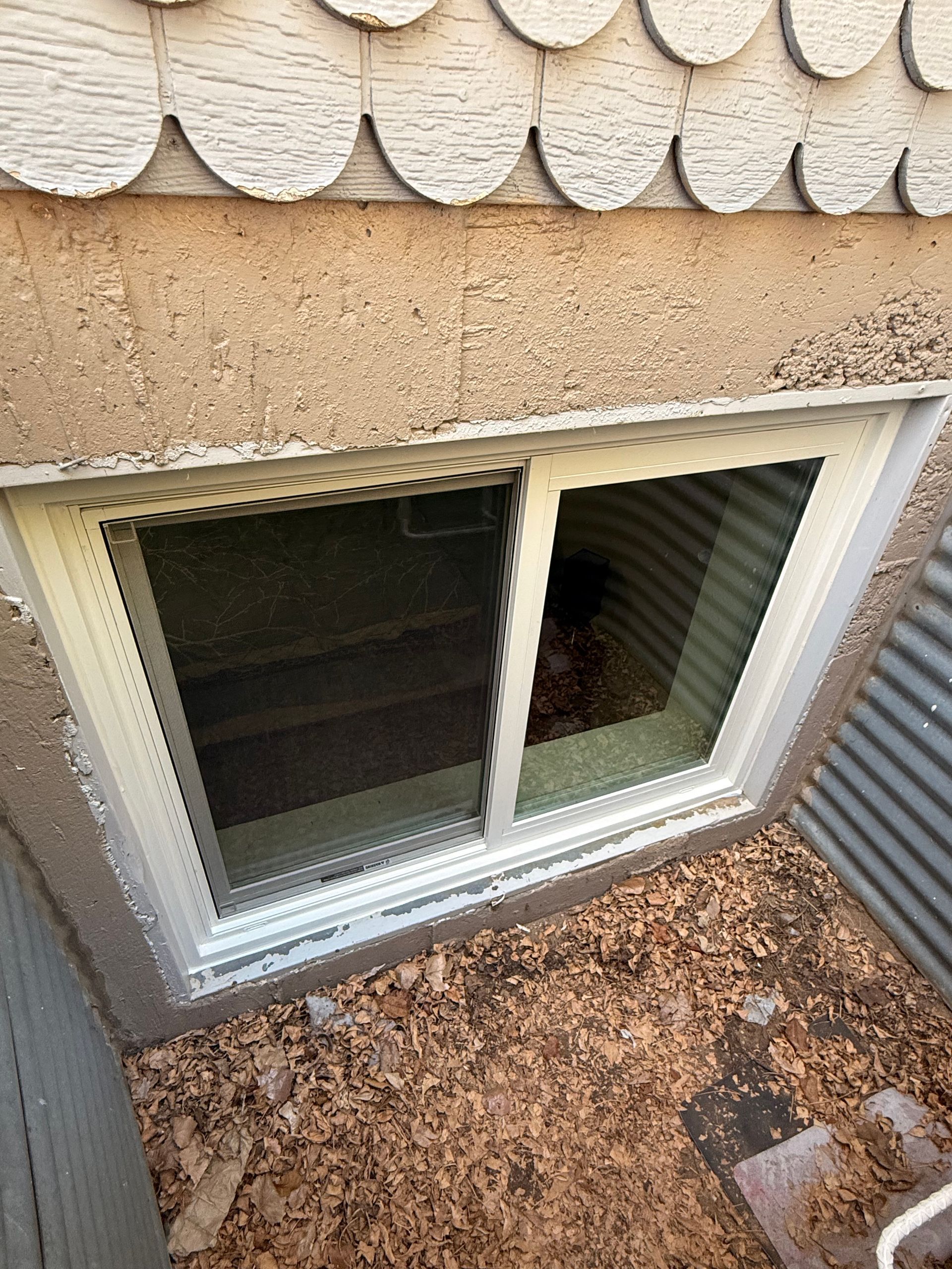 There is a window in the basement of a house.