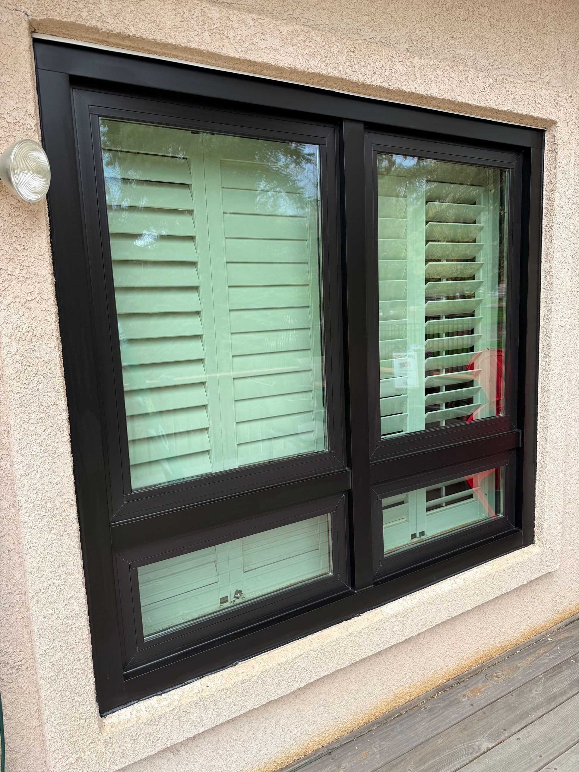 A large window with shutters on it is on the side of a building.