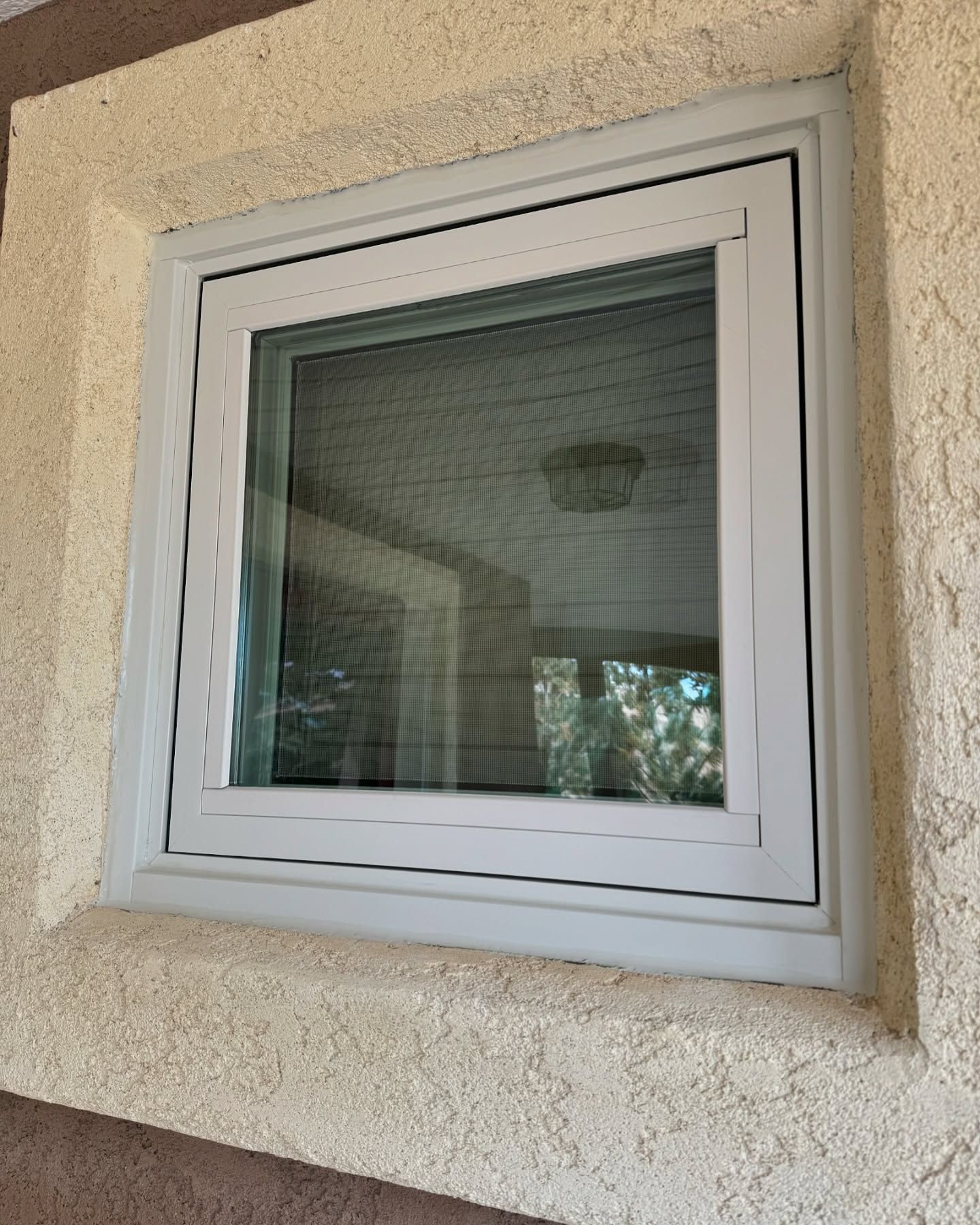 A white window is on the side of a building.