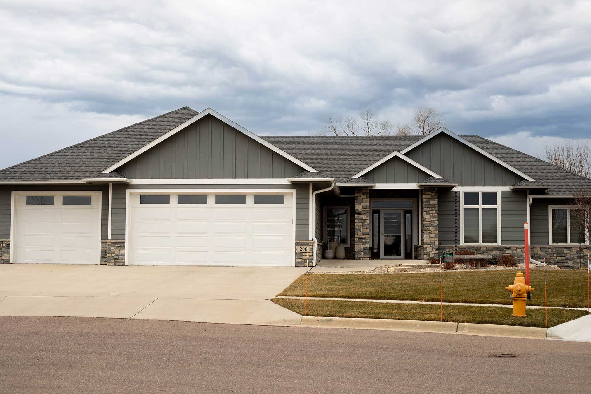 a large house with white garage doors and a fire hydrant in front of it