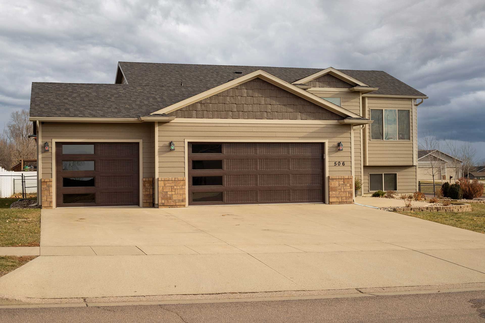 a huge house with two brown garage doors and a large driveway