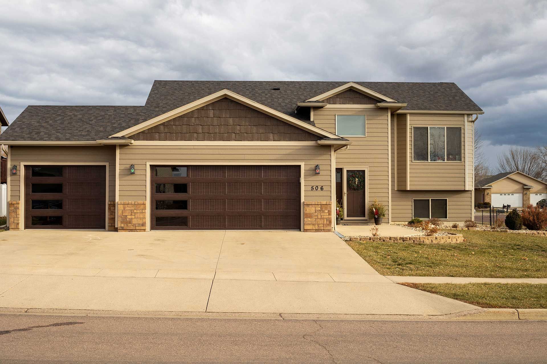 a large house with two garage doors and a cloudy sky in the background