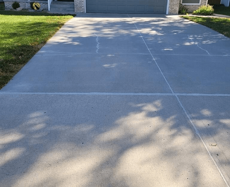 A concrete driveway with a garage in the background
