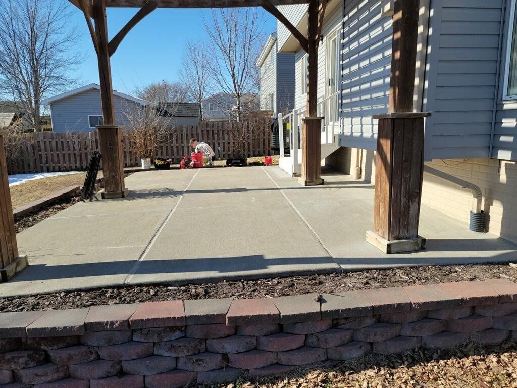 A patio with a pergola and a brick wall in front of a house