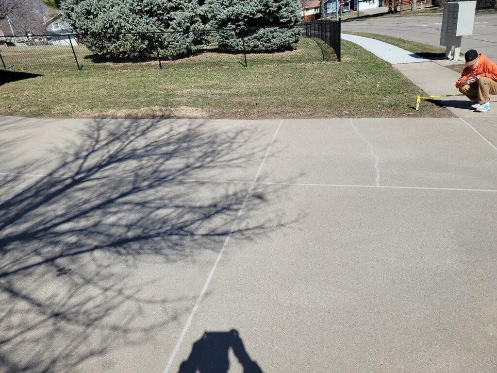 A shadow of a person is cast on a concrete driveway