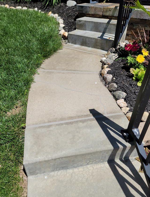 A concrete walkway with stairs leading up to a house